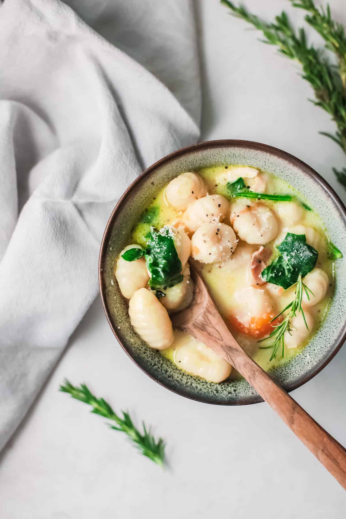 the finished instant pot chicken gnocchi soup served in a ceramic bowl with a wooden spoon