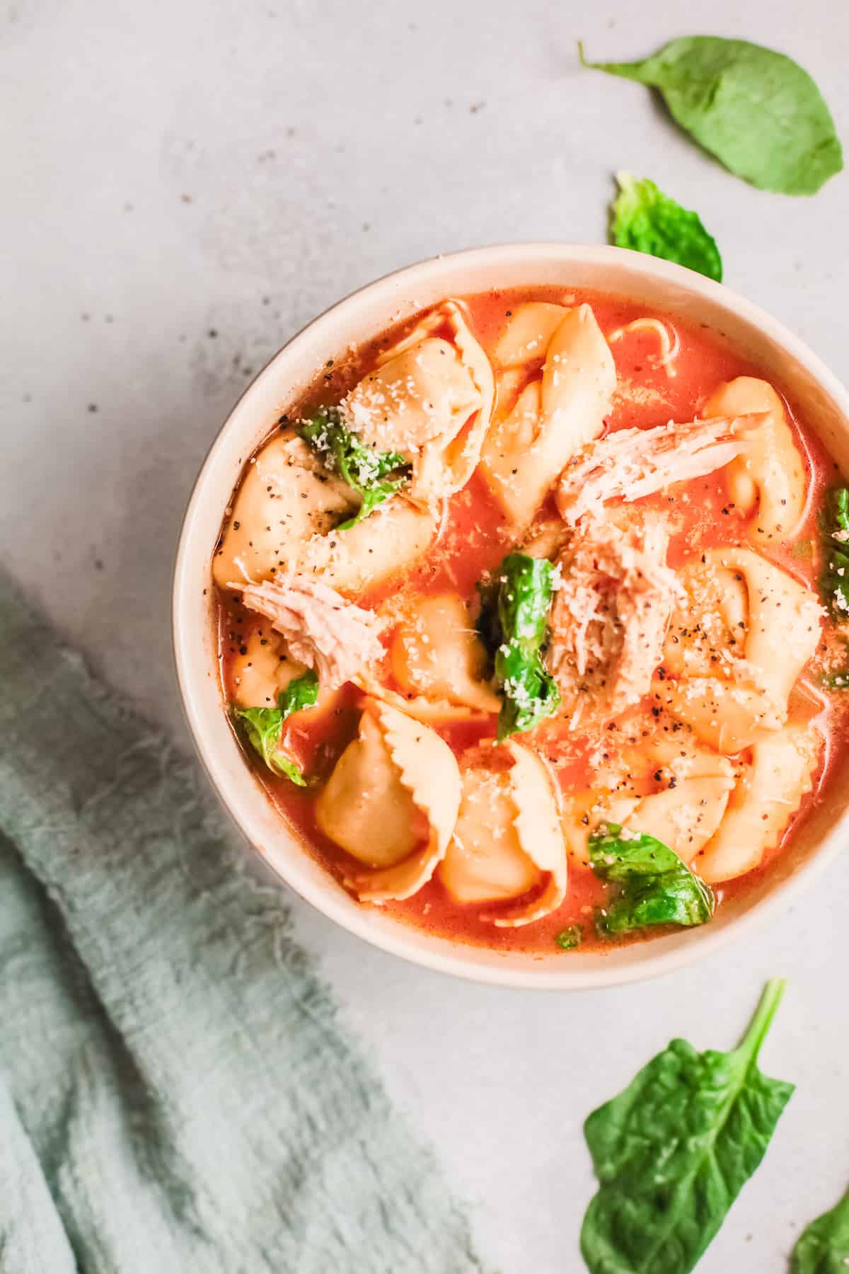 a bowl full of instant pot chicken tortellini soup with spinach and cheese