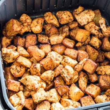 close up view of chicken and potatoes in the air fryer basket