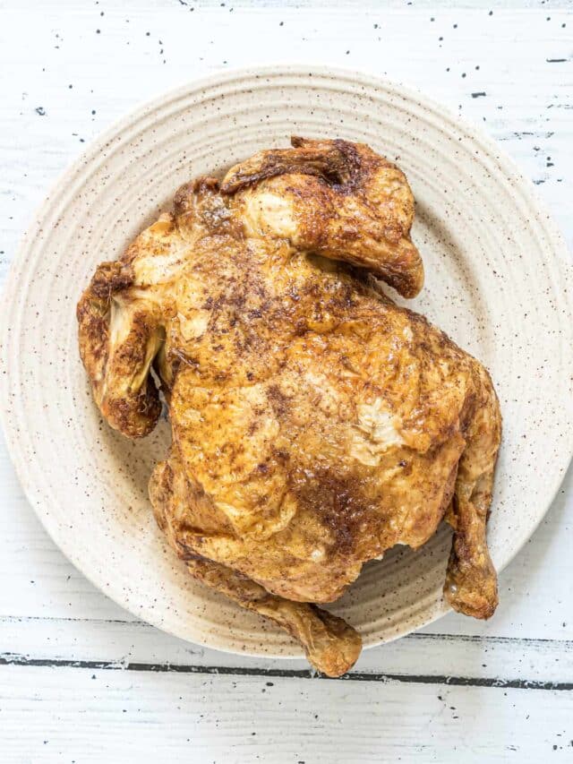 the finished air fryer whole chicken served on a white plate