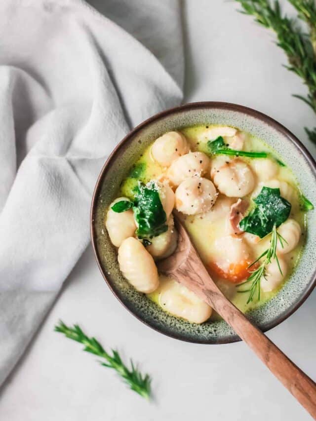 the finished instant pot chicken gnocchi soup served in a ceramic bowl with a wooden spoon