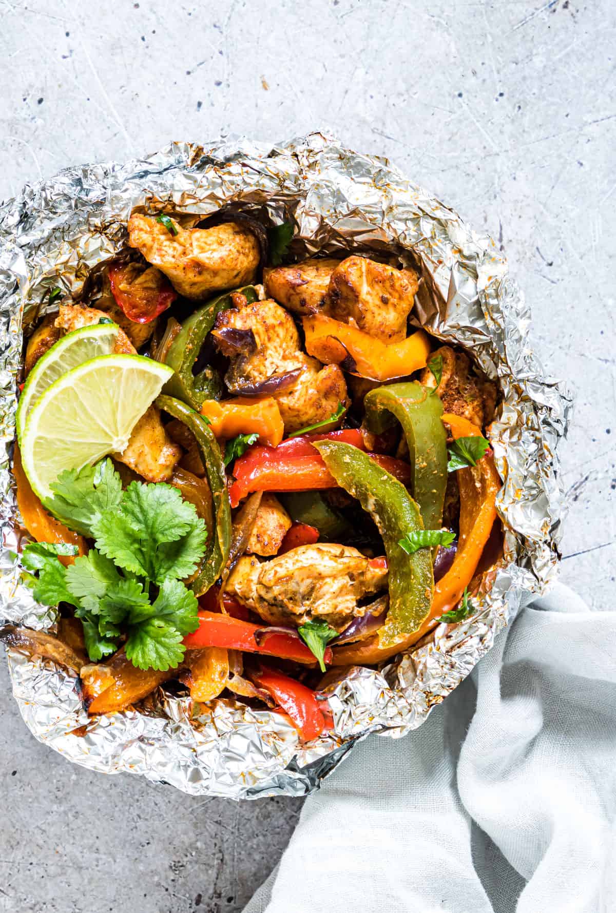 Easy cooked campfire chicken Fajitas in a foil packet with lime and cilantro garnish