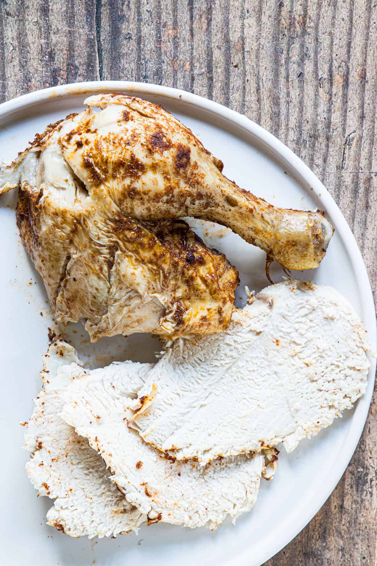 cooked whole chicken sliced and ready to serve on a white plate