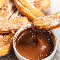 churros being dipped in a chocolate sauce