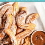 A PLATE OF CHURROS WITH CHOCOLATE ON THE SIDE