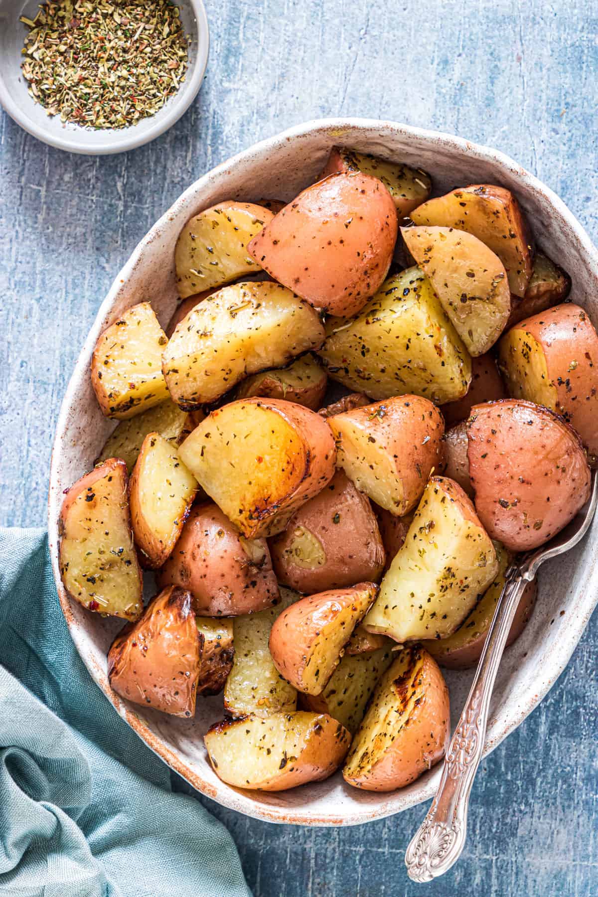 A bowl of cooked red potatoes with some seasoning on the saide