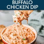 A BOWL OF BUFFALO CHICKEN DIP WITH A CHIP DIPPING INTO IT