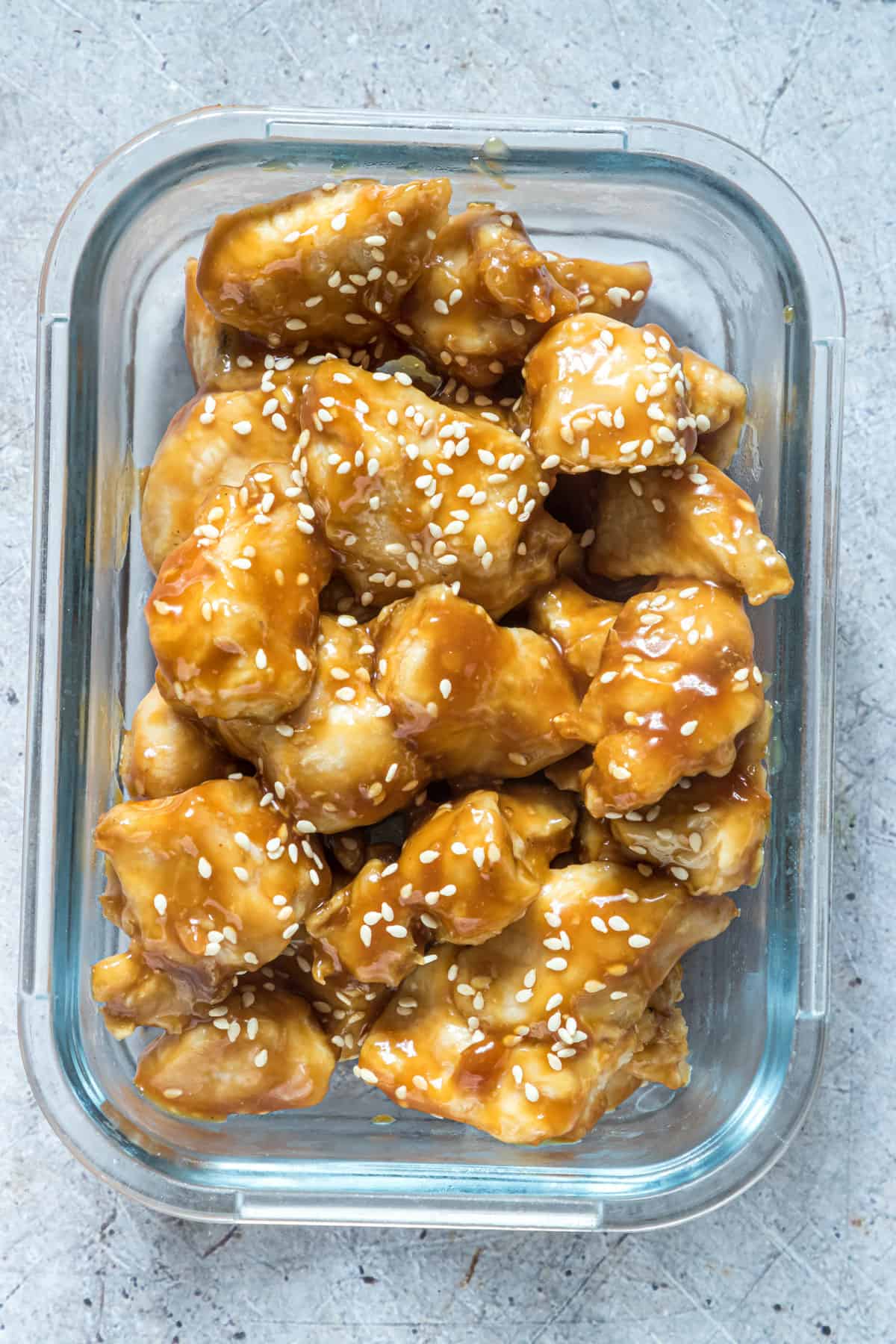 a serving of the air fryer orange chicken inside a glass food storage container