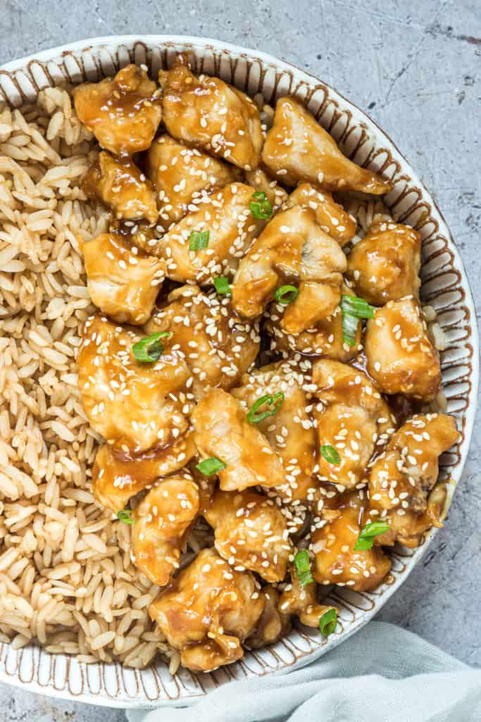 close up view of the completed air fryer orange chicken served with brown rice