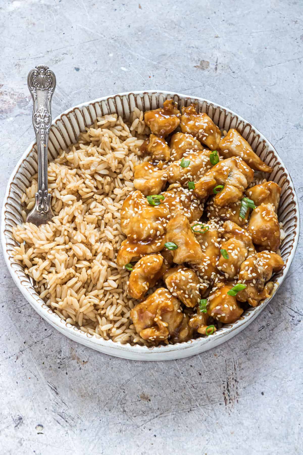 a ceramic bowl filled with air fryer orange chicken and rice