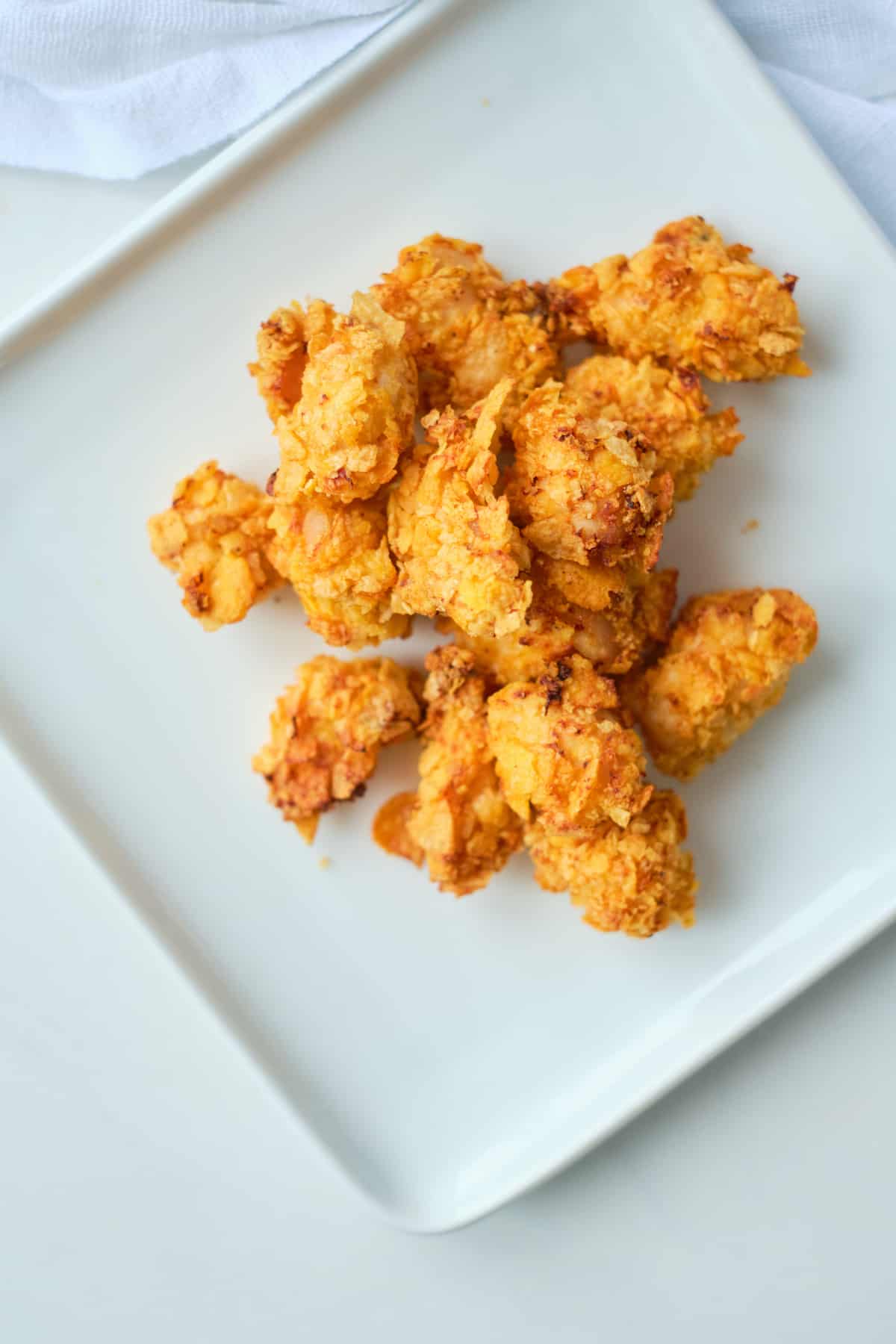 top down view of a serving of air fryer popcorn chicken on a square white plate