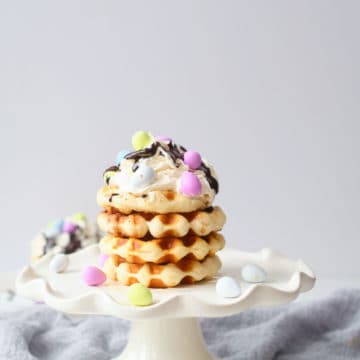 side view of 3 of the biscuit waffles stacked on a white cake stand