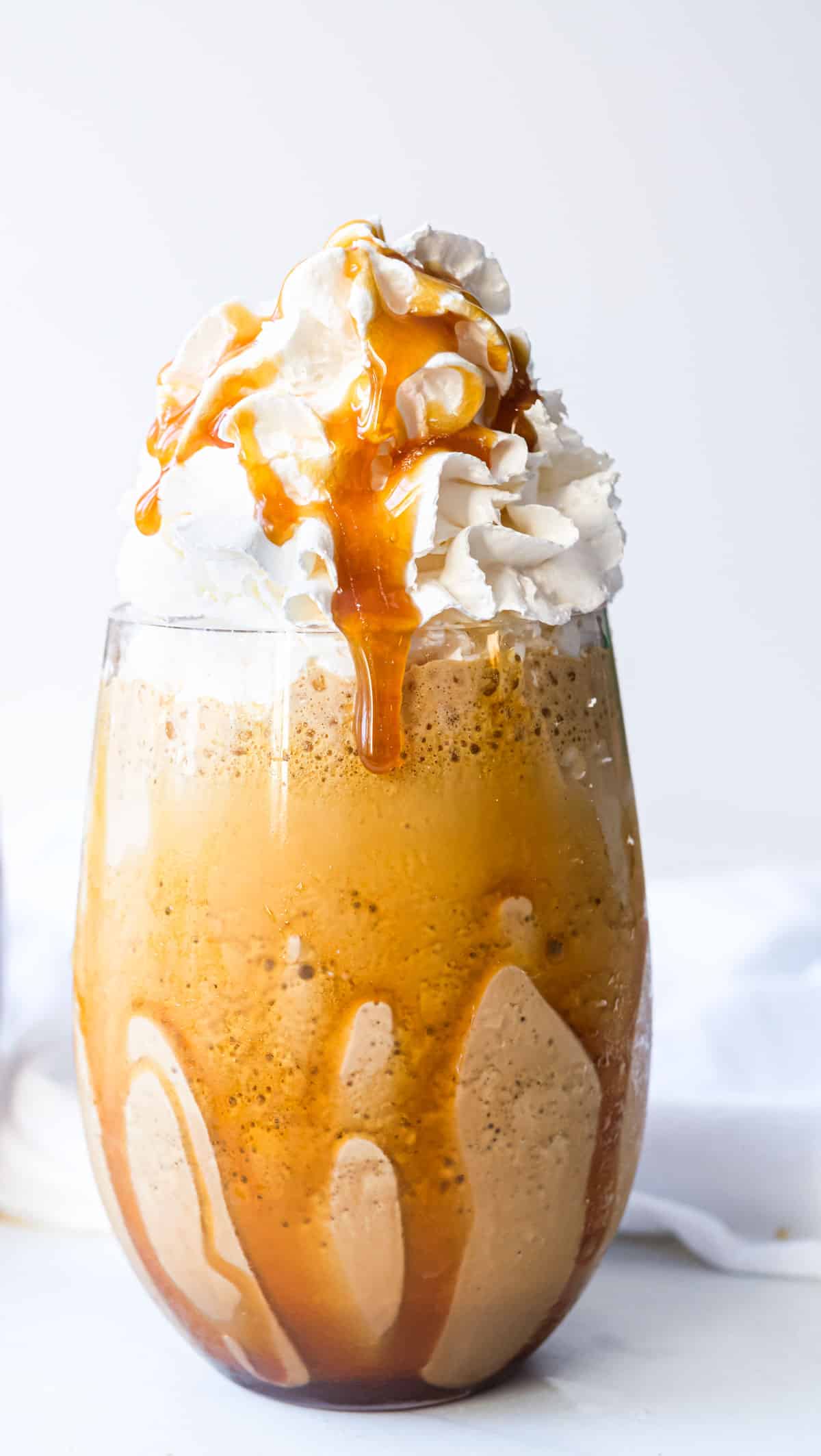 one completed caramel frappe topped with whipped cream and caramel sauce
