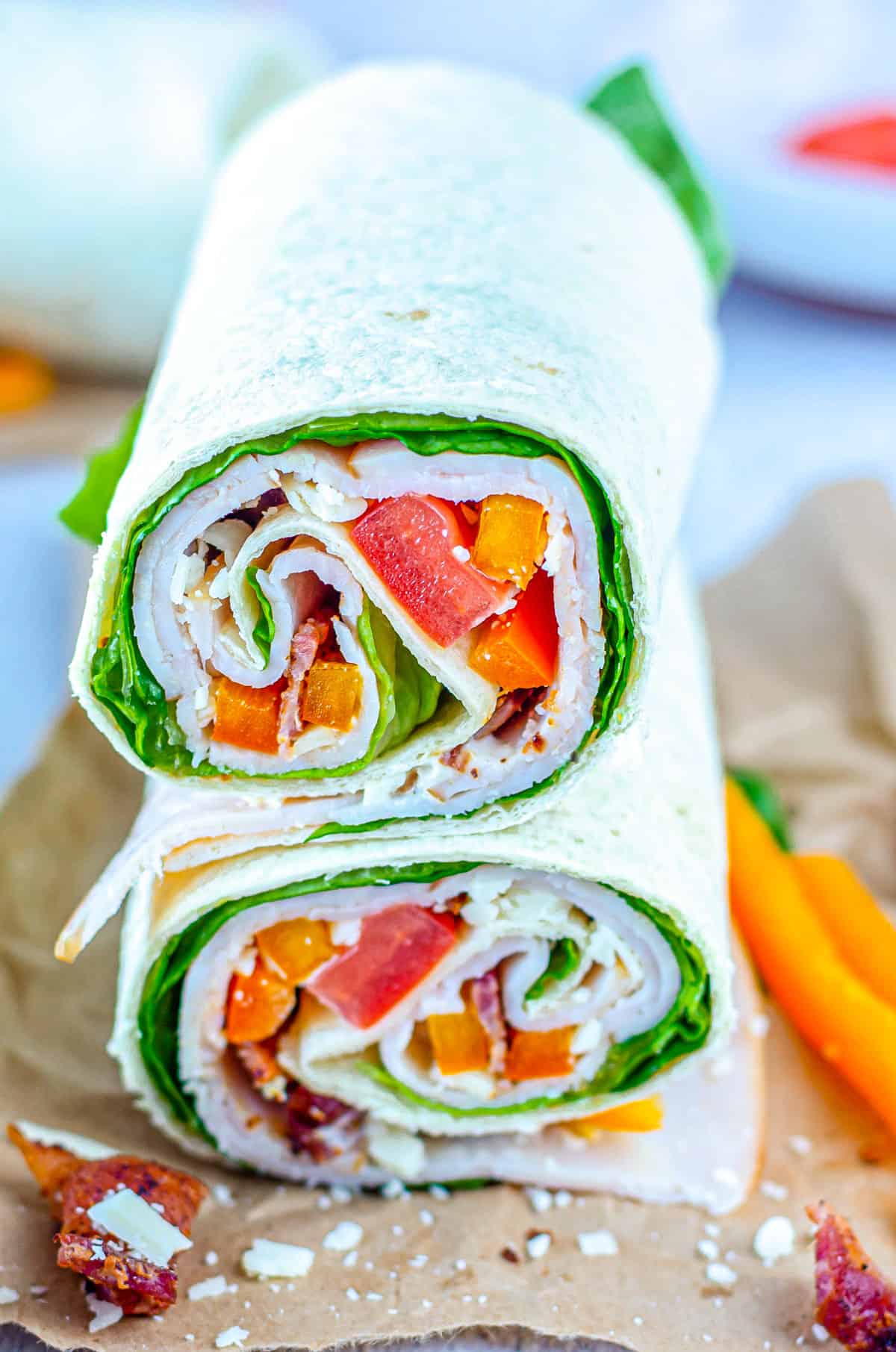 the completed chicken wrap with bacon and ranch served on parchment paper with carrot sticks