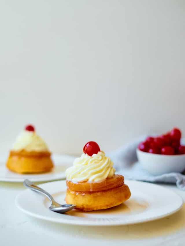 two pineapple upside down cupcakes served on white plates with silver forks
