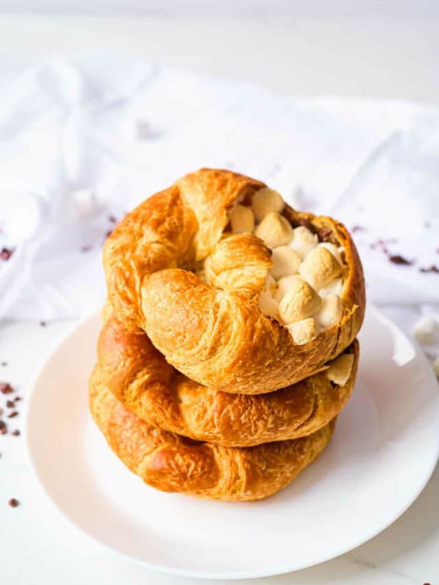 three stuffed croissants stacked vertically on a white plate