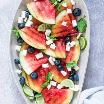 grilled watermelon salad with feta and blueberries on a plate served with a cloth napkin