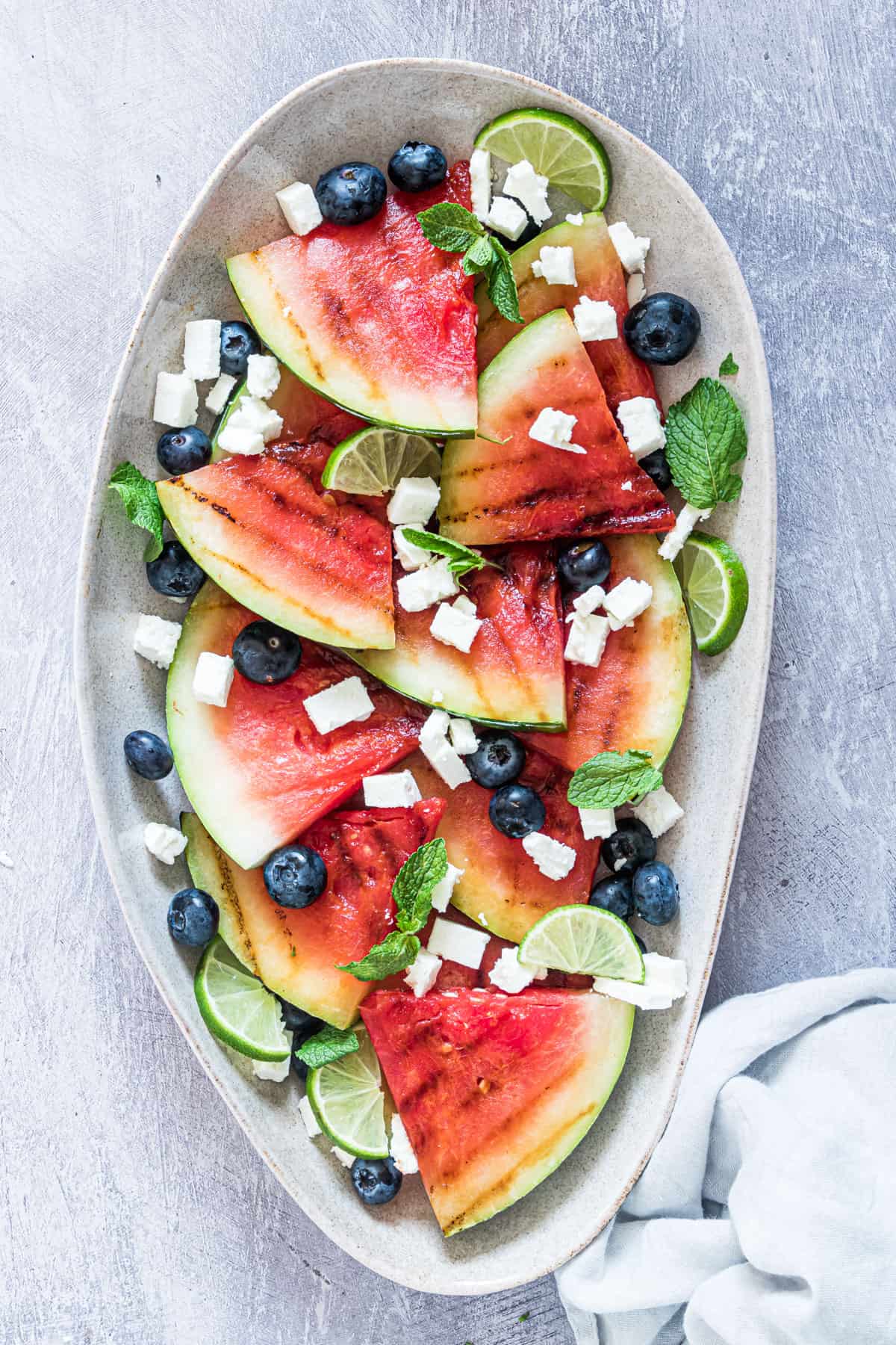 grilled watermelon salad with feta and blueberries on a plate served with a cloth napkin