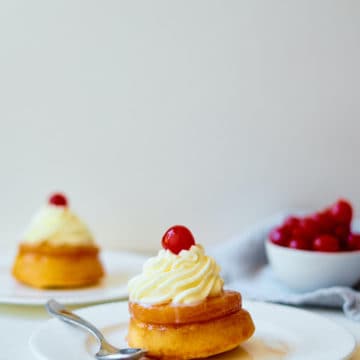 two pineapple upside down cupcakes served on white plates with silver forks