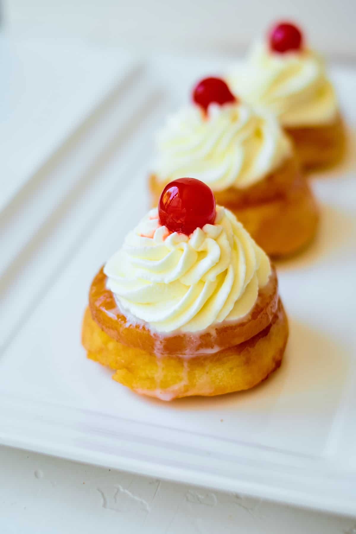 three of the finished pineapple upside down cupcakes on a white serving tray