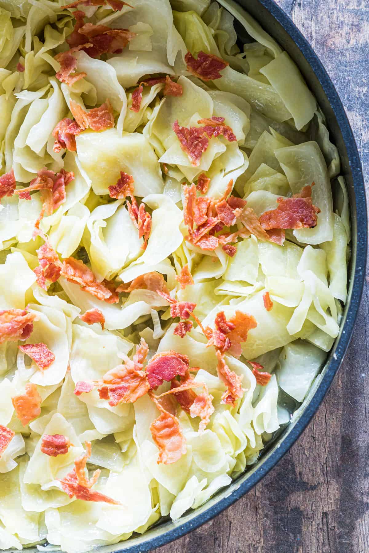 close up view of the cooked cabbage with bacon side dish inside a skillet