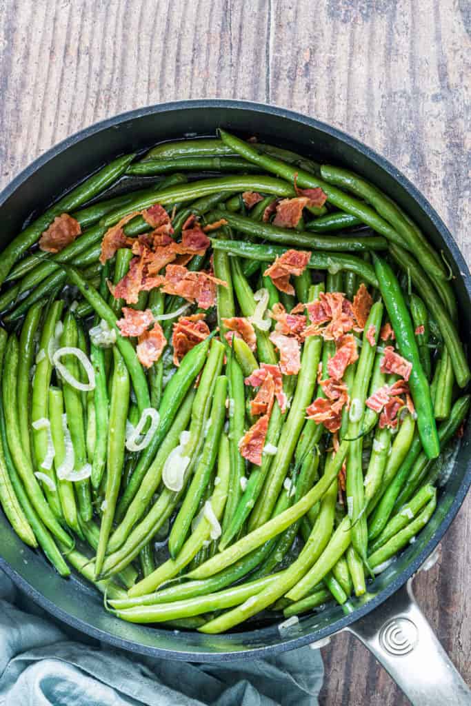 smothered green beans in a skillet set on a cloth napkin