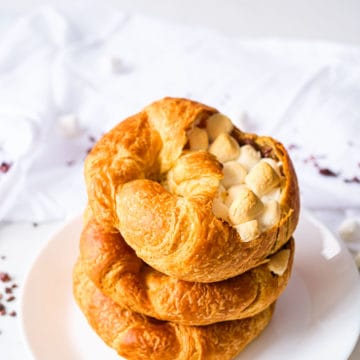 three stuffed croissants stacked vertically on a white plate