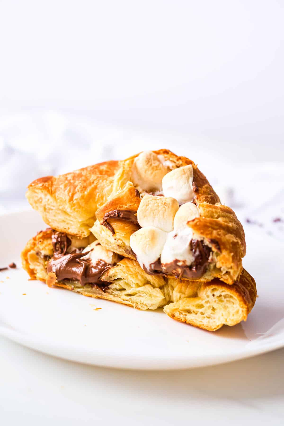 one completed stuffed croissant breakfast boat cut on half and served on a white plate