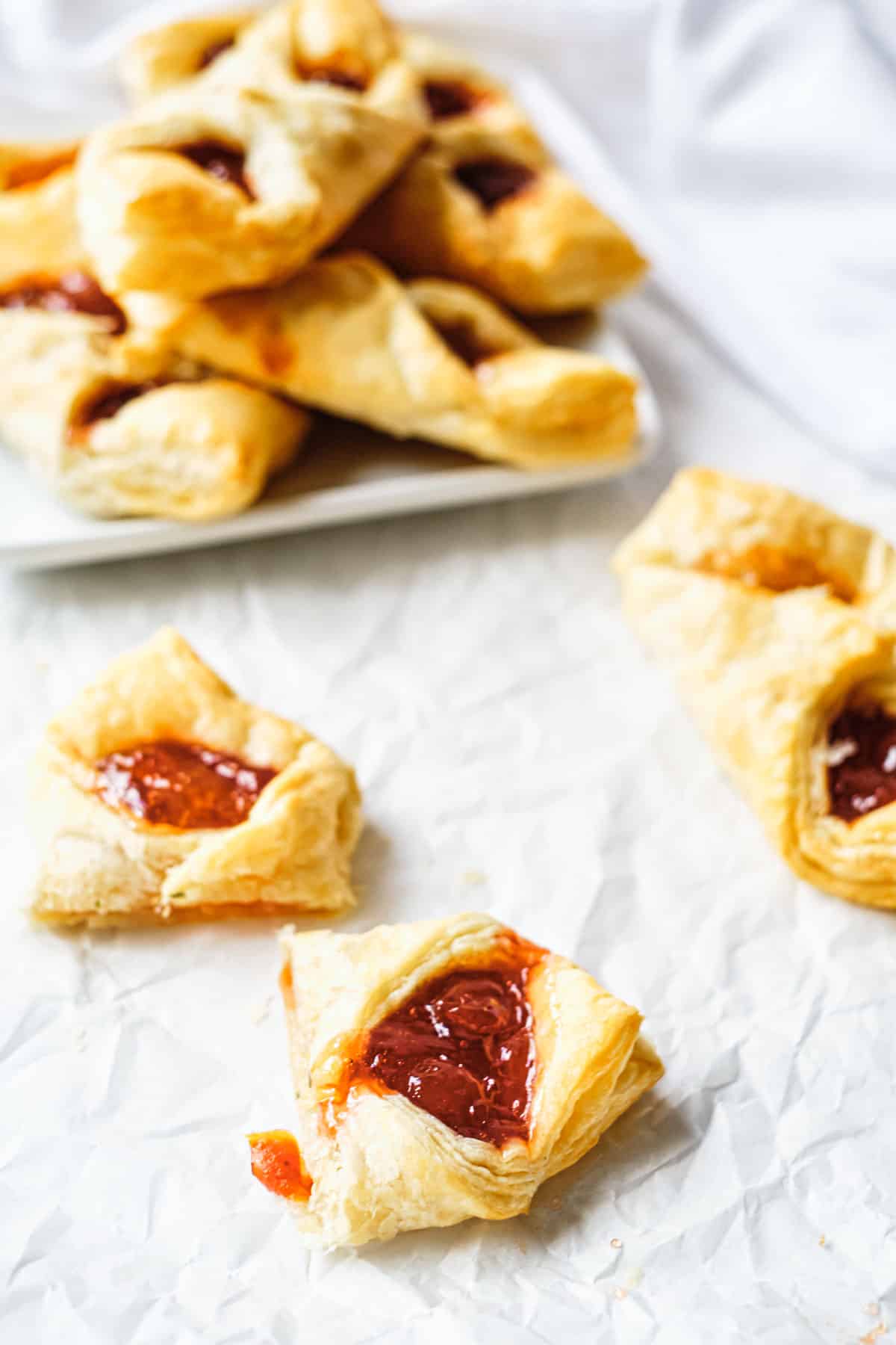 three puff pastry breakfast bites set in front of a plate filled with the rest