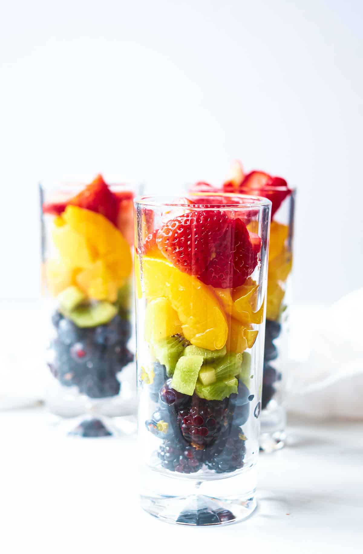 3 glasses of rain bow fruit in layers on a table