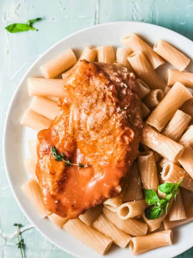 close up view of the completed cajun chicken recipe served over pasta on a white plate