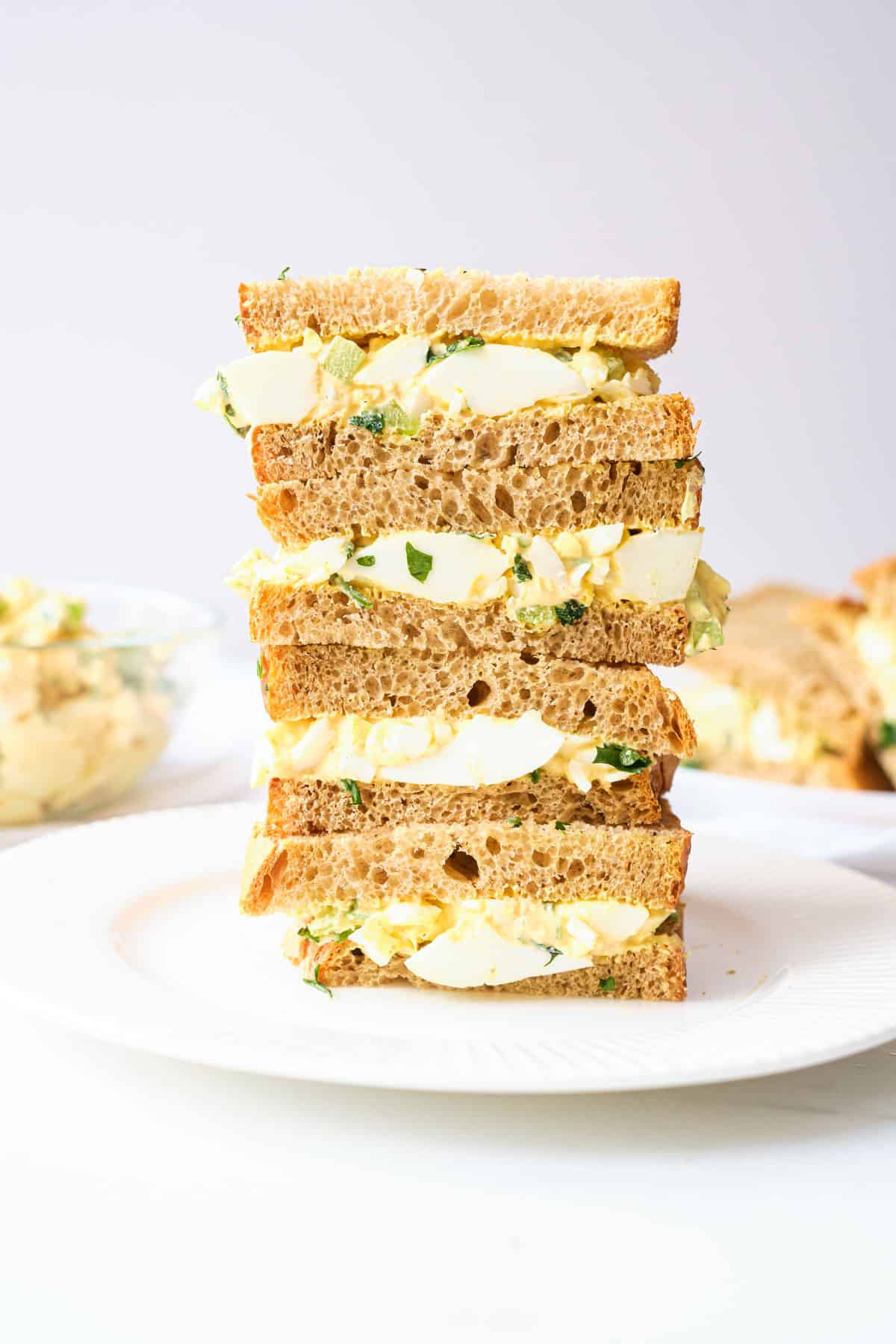 four egg salad sandwiches stacked on top of each other