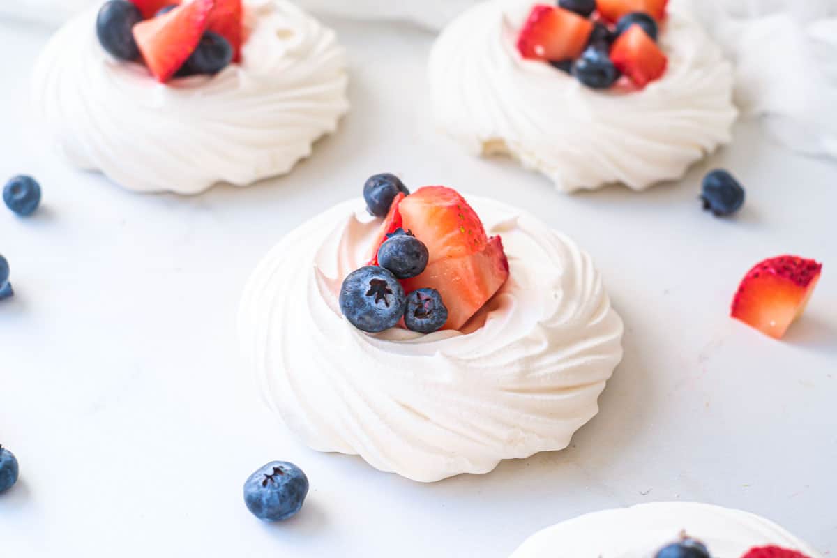 some mini pavlova nests filled with strawberries and blueberries