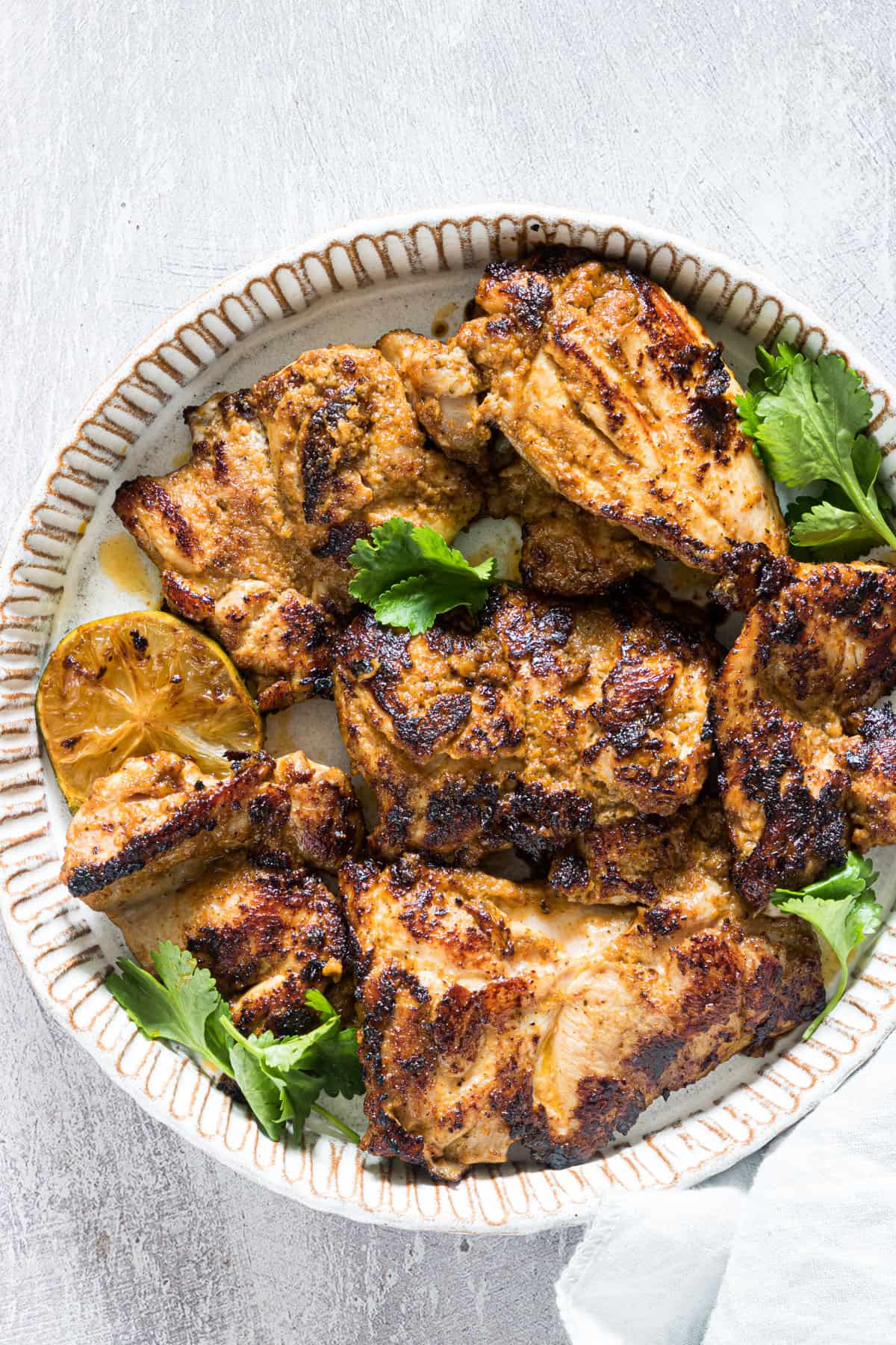 a plate of grilled chipotle chicken with cilantro and lime garnish