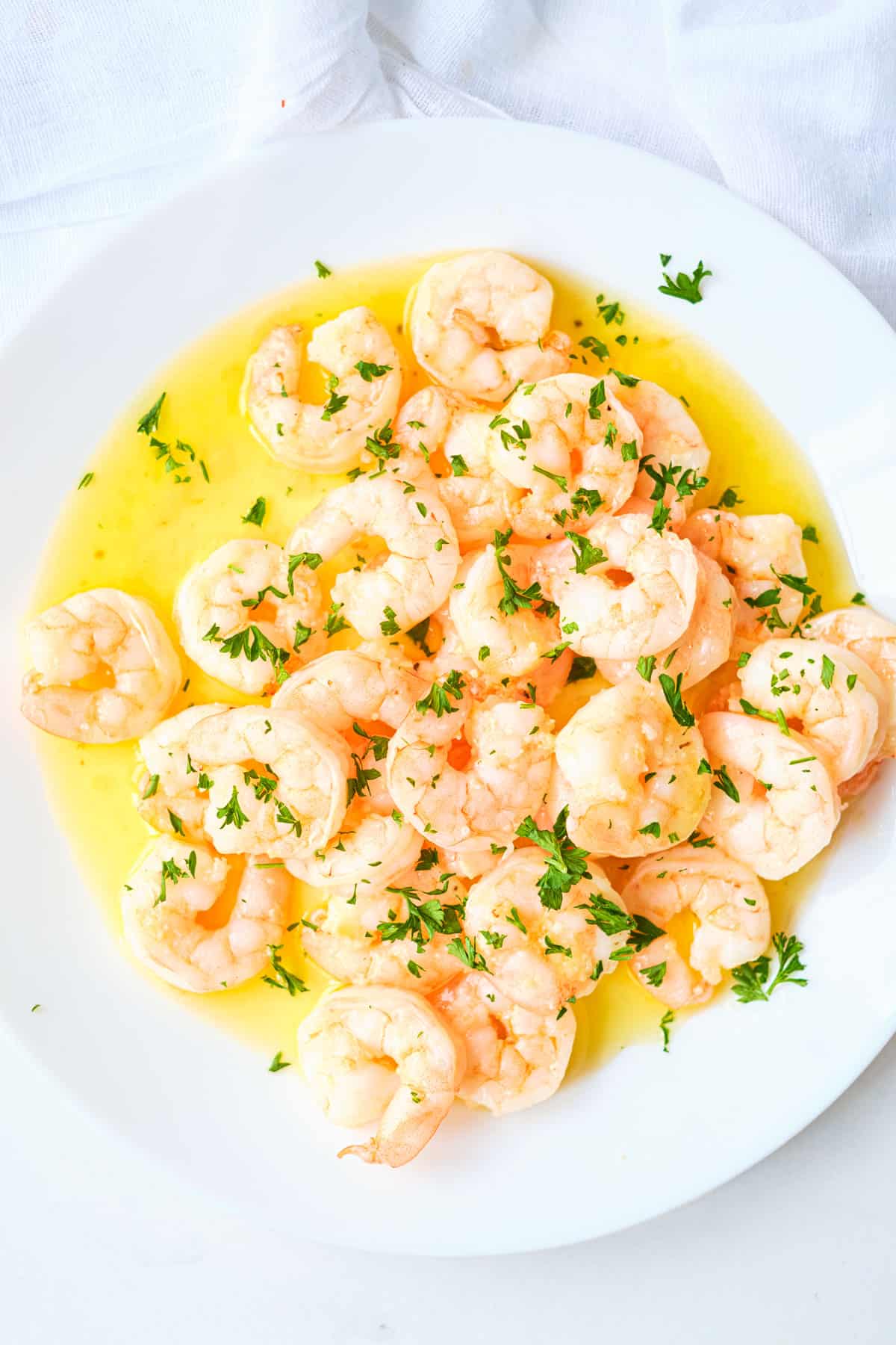 garlic butter shrimp on a plate with chopped herbs