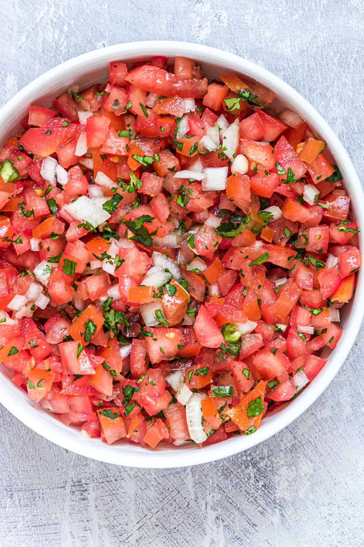 close up view of the finished pico de gallo in a white bowl
