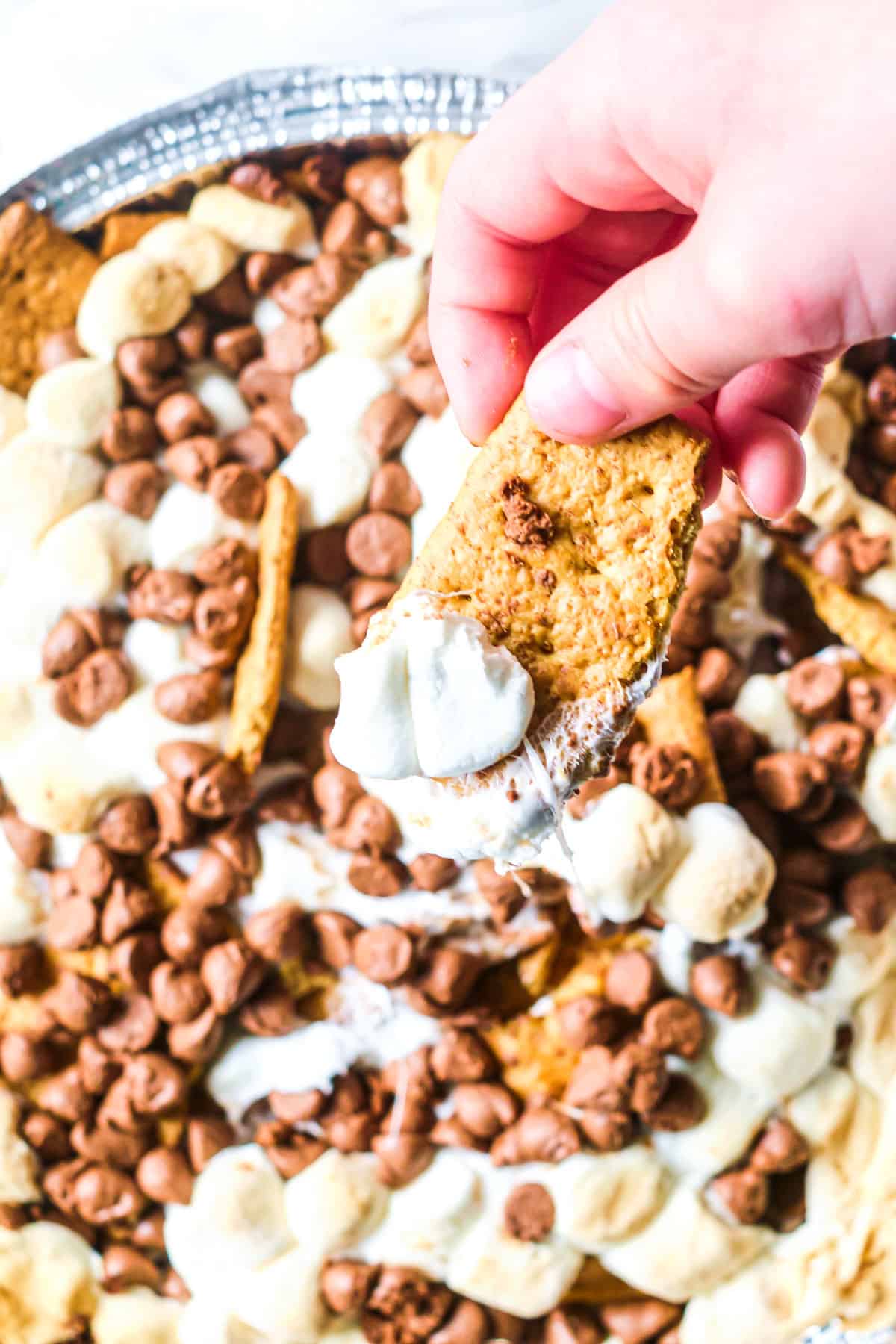 a hand taking some smores nachos form a tray