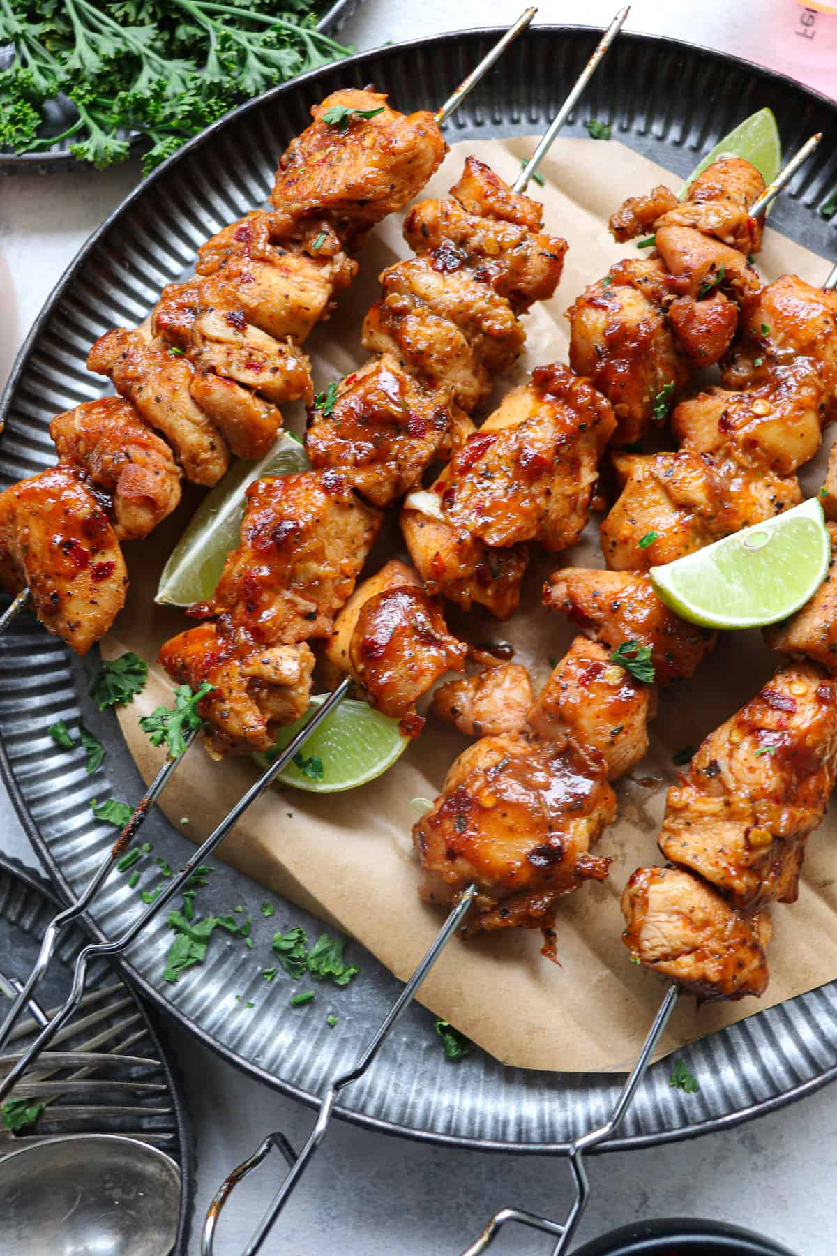 close up view of the finished chicken satay skewers served on a plate with lime wedges
