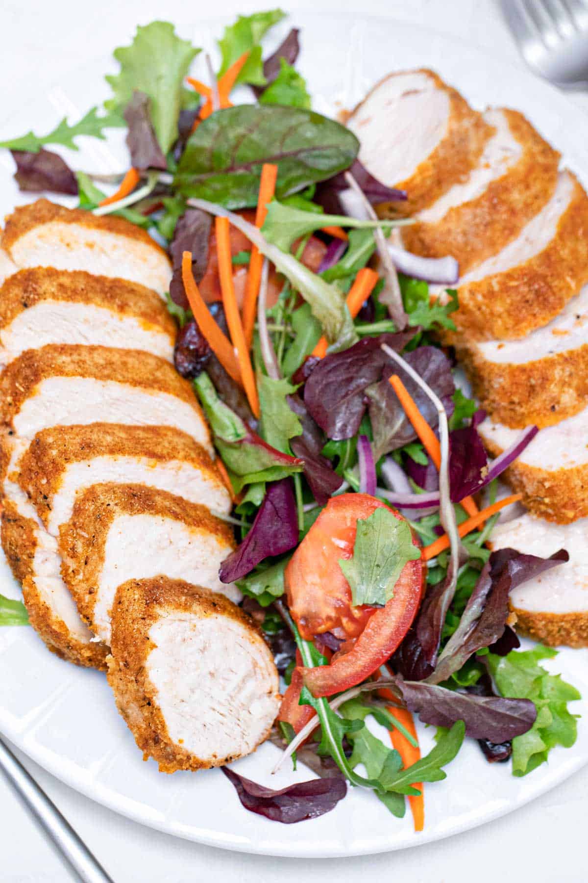 top down view of the completed air fryer chicken breast sliced and served with salad greens