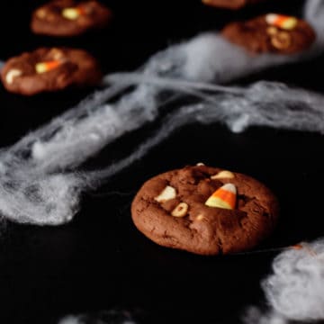 candy corn cookies served on a black mat with fake spider web decor