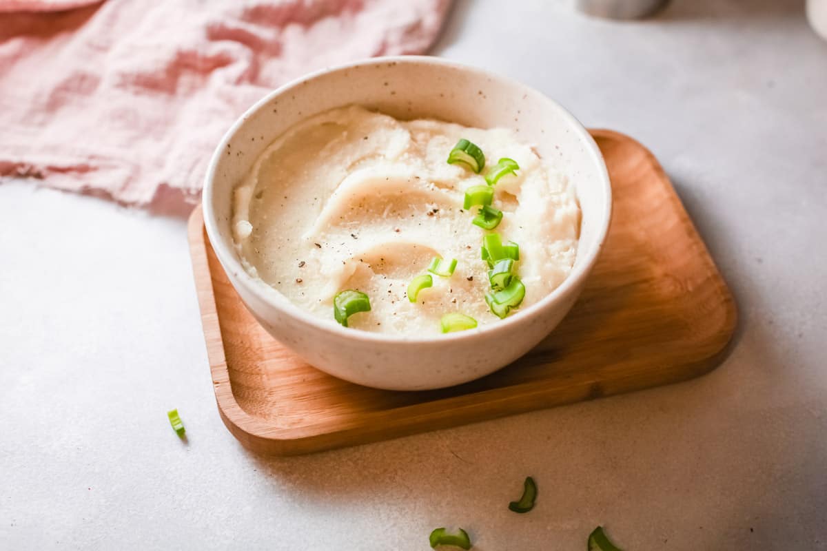 the completed roasted garlic mashed potatoes in a white serving bowl