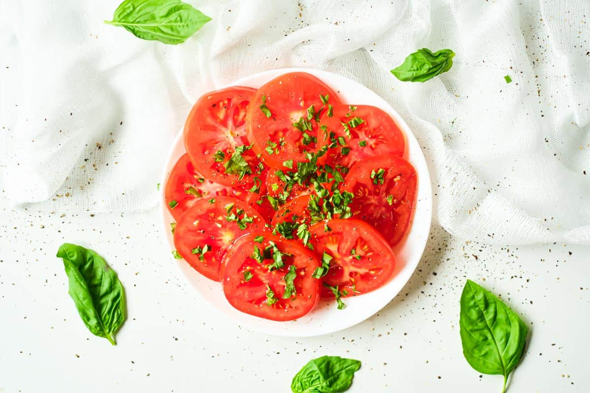 marinated tomatoes with basil served on a white plate