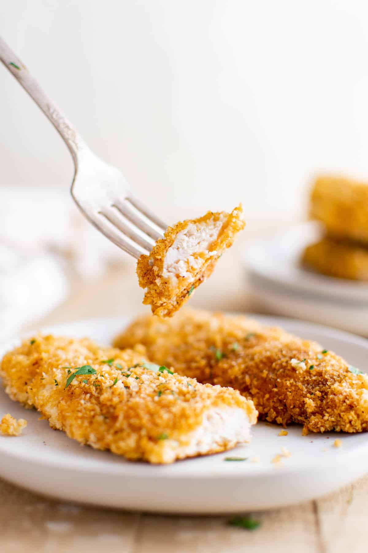 a fork removing one bite from a serving of oven baked chicken tenders