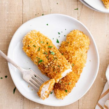 one serving of baked chicken tenders on a plate with a fork removing a bite