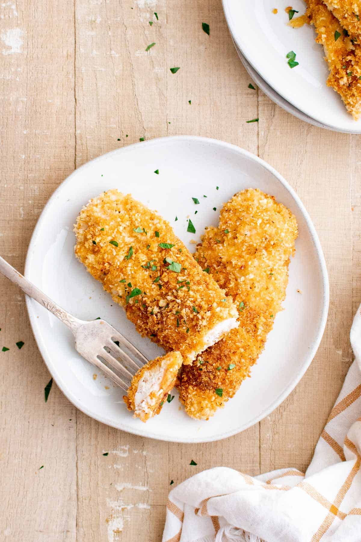 one serving of baked chicken tenders on a plate with a fork removing a bite