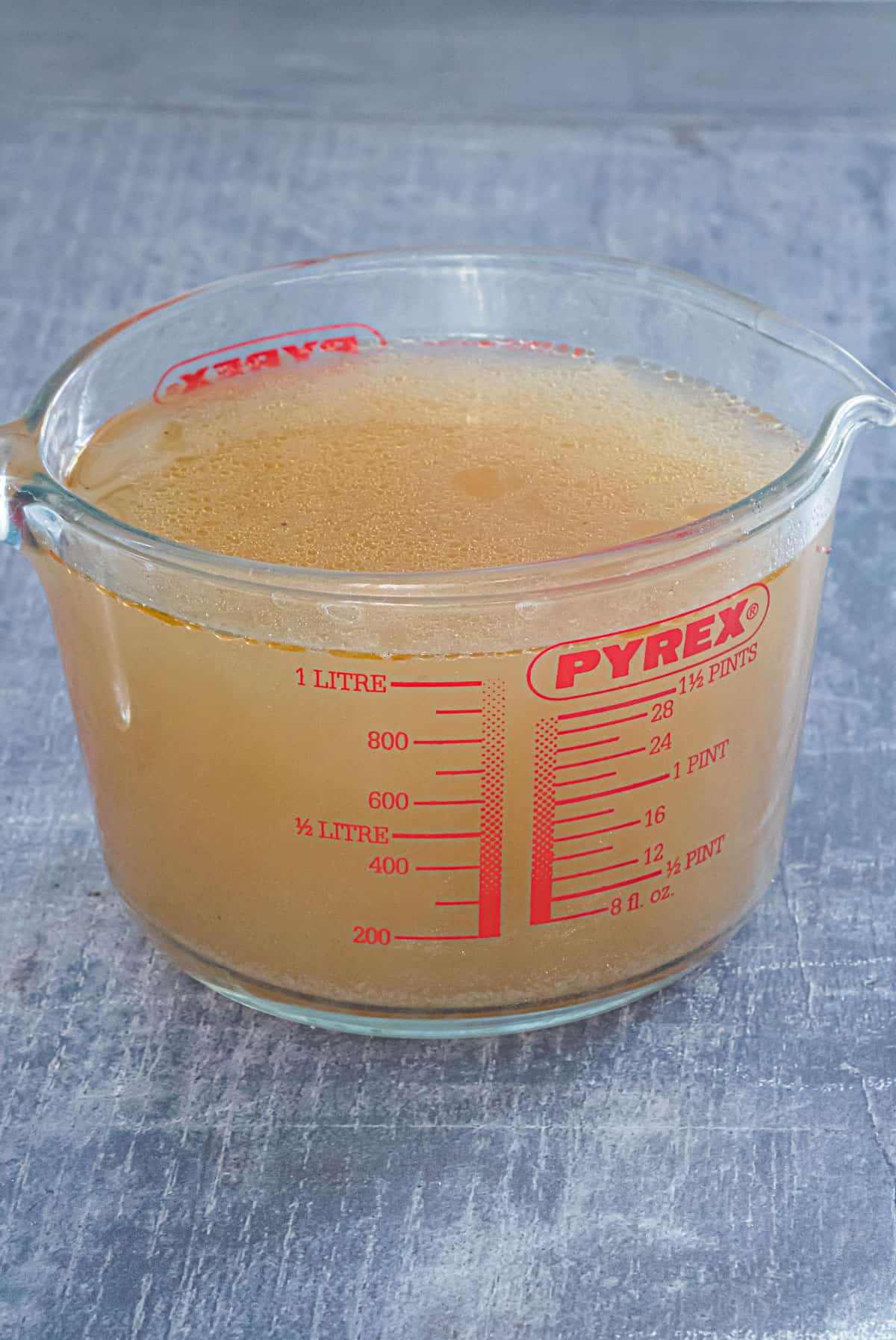 close up view of a measuring cup containing the completed instant pot chicken stock