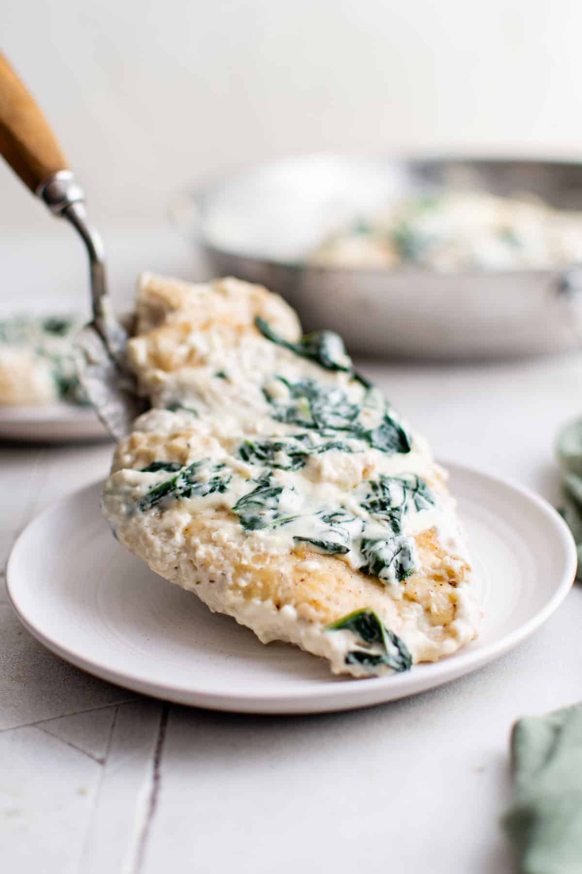 one portion of chicken florentine being put onto a dinner plate