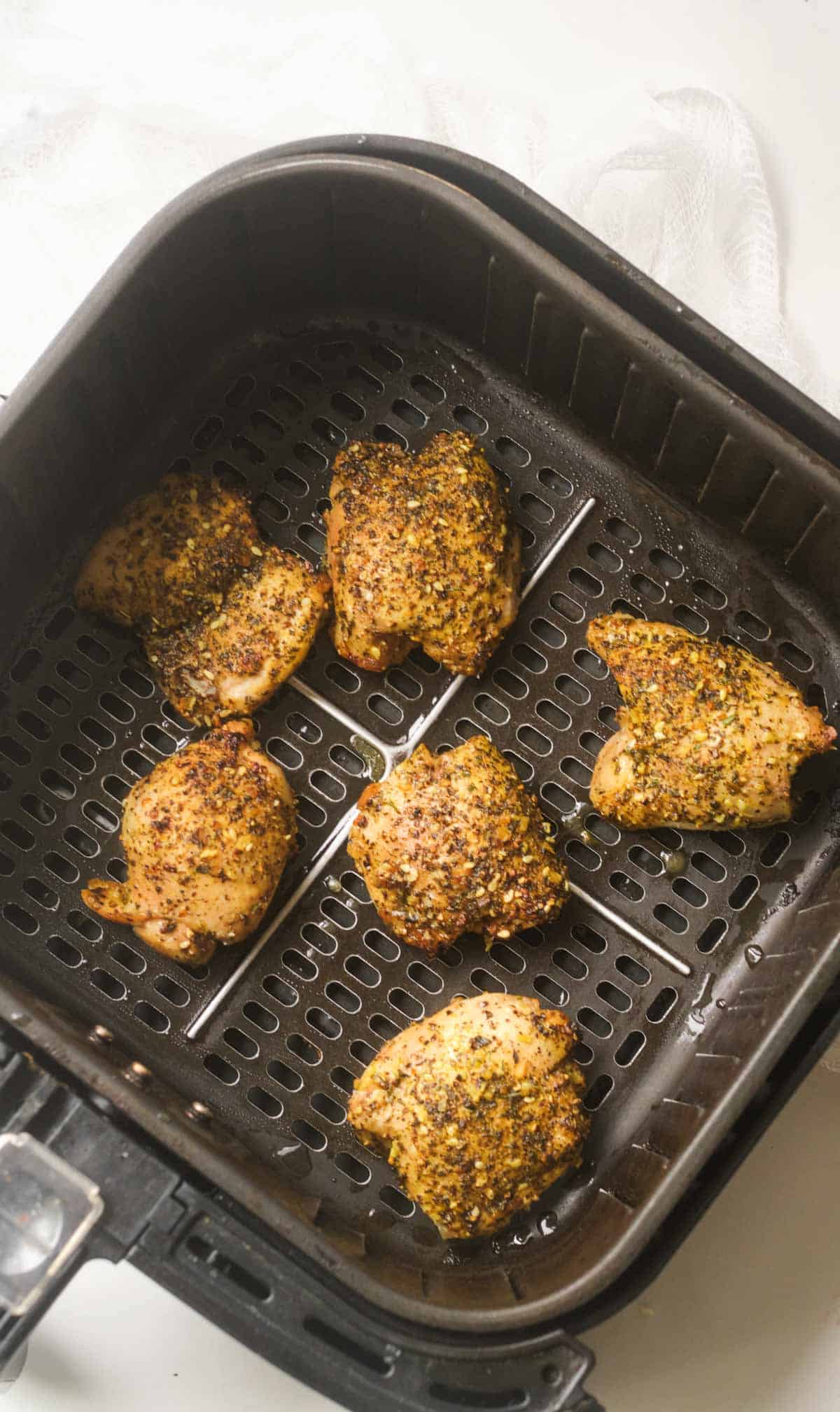 top down view of the cooked lemon pepper chicken thighs inside the air fryer basket