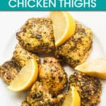 lemon pepper chicken thighs on a plate with lemon wedges