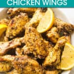 lemon pepper chicken wings on a plate with lemon wedges